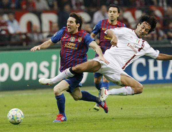 Barcelona's Lionel Messi (L) is challenged by AC Milan's Alessandro Nesta during their UEFA Champions League quarter final first leg soccer match at the San Siro stadium in Milan March, 28 2012.