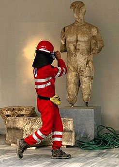 A Greek firefighter takes photos of an ancient Greek statue on the yard of the archaeological museum in Ancient Olympia
