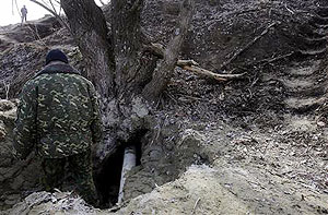 A rescue worker stands at the entrance to an underground hideout where some members of a doomsday cult emerged after a six months stay 