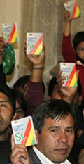 People hold up the proposed new constitution during a ceremony at the presidential palace in La Paz