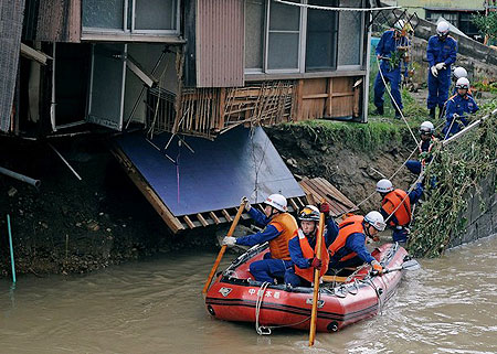 Japanese firefighters sit in a rescue boat as they search for a missing 80-year-old woman at the Iga river near her damaged house in Okazaki, Aichi prefecture on August 29, 2008.