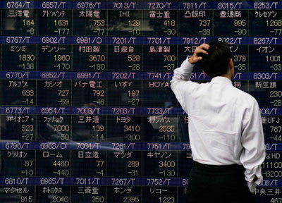 Man looks at video display showing Japanese stock prices in Tokyo 