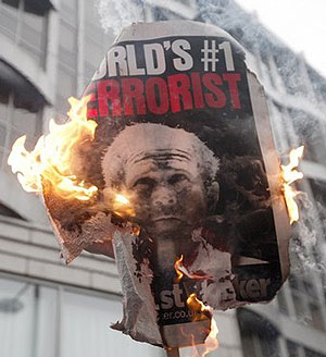 A placard bearing a portrait of U.S. President George Bush is burned outside the Israeli Embassy during a demonstration against the conflict in Gaza, in London 