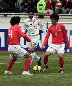 South Korea's Cho Yong-hyung (L) passes the ball to team mate Oh Beom-seok as Iran's Vahid Hashemian looks on during their 2010 Fifa World Cup Asia qu
