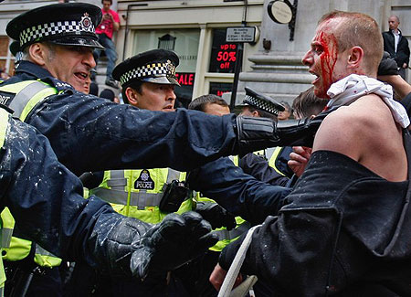 A bleeding protester is held back by police as Anti capitalist and climate change activists demonstrate in the City of London on April 1, 2009 