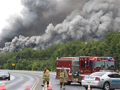 Plumes of smoke from a burning chemical plant fill the sky as emergency workers form a roadblock west of Bryan, Texas, Thursday, July 30, 2009.  (AP Photo)