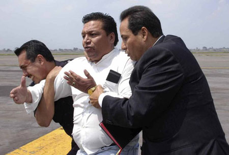 Bolivian-born Jose Flores (C), clutching a bible, is taken away by plainclothes police officers at the international airport in Mexico City September 9, 2009.