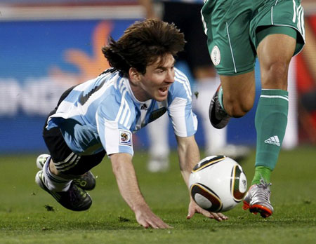 Argentina's Lionel Messi falls as he battles for the ball with Nigeria's Peter Odemwinge during the 2010 World Cup Group B soccer matchat Ellis Park stadium in Johannesburg June 12, 2010.
