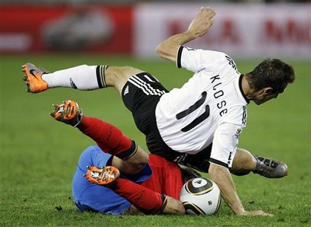 Germany's Miroslav Klose, right, falls over Spain's Gerard Pique, left, as they compete for the ball during the World Cup semifinal soccer match between Germany and Spain at the stadium in Durban, South Africa, Wednesday, July 7, 201