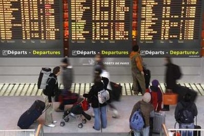 Passengers look at a flight departure information board in a terminal at the Charles-de-Gaulle airpo