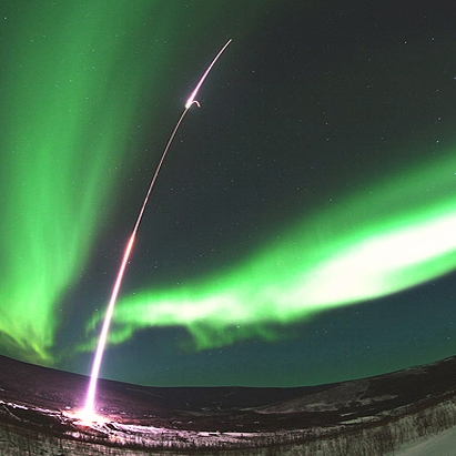 موشک دو مرحله‌ای را در میان آسمانی که به نور سبز رنگ شفق قطبی آلاسکا 