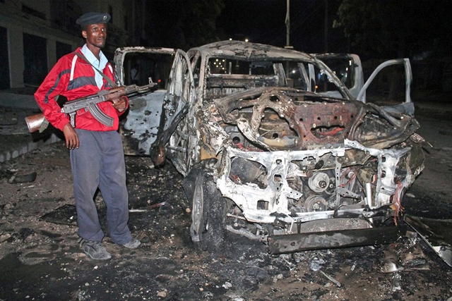 Ein Soldat steht in Mogadiscio vor einem ausgebrannten Auto